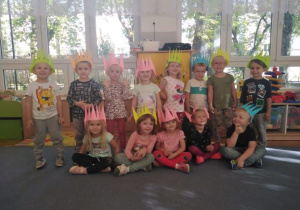 Dzieci ustawione w dwóch rzędach z kolorowymi koronami na głowie.